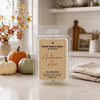 A clear plastic clamshell package of Country Cracker Candle 'Autumn Air' soy wax melts sits on a kitchen counter. The package has a tan paper label with red script text.